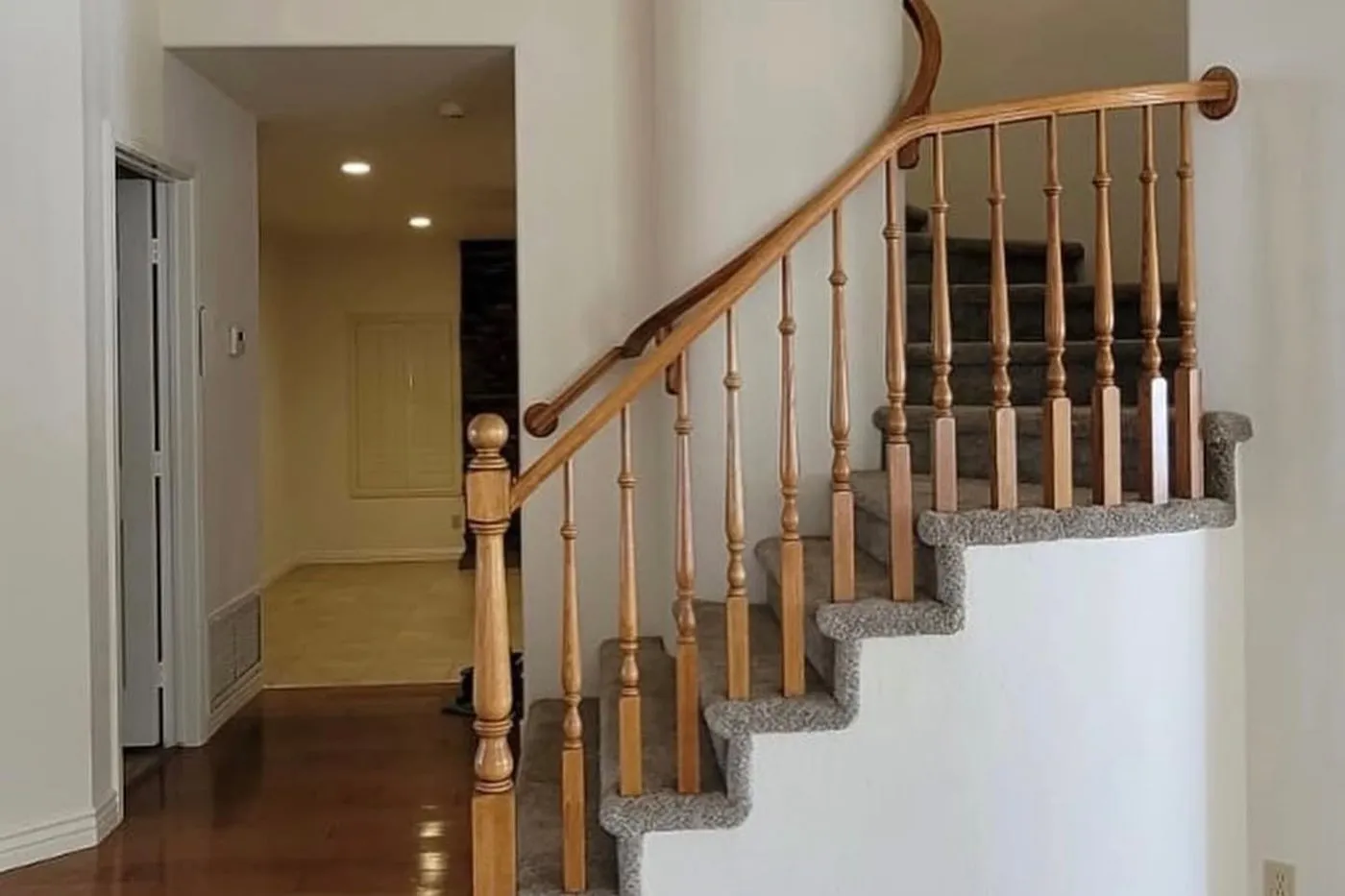 A curved staircase with a shaped oak handrail and turned newel post