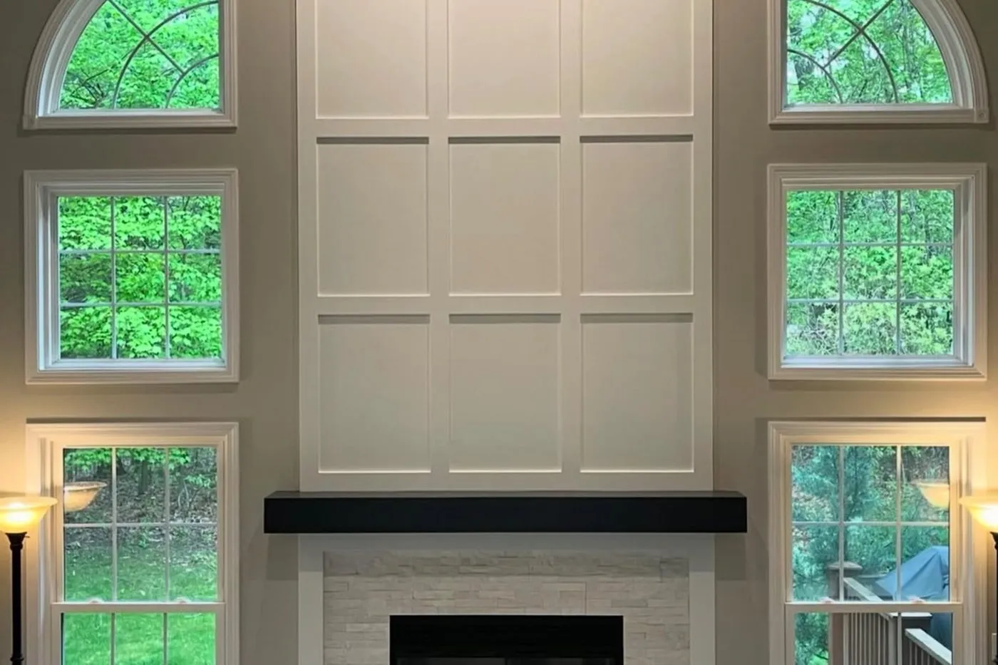 A double-height living room with arched windows and a full-height panelled fireplace