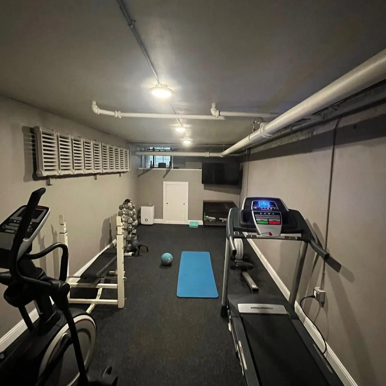 A finished basement in an Ontario home with exposed ductwork and mechanical services